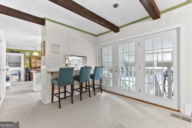 2540 Sugar Hill Rd, Unadilla, GA 31091 - carpeted dining room featuring beamed ceiling, a textured ceiling, french doors, wood walls, and tile patterned floors