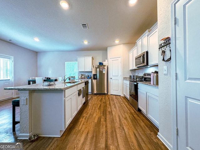 534 Meadows Farm Dr, Monroe, GA 30655 - kitchen featuring appliances with stainless steel finishes, dark wood finished floors, a kitchen island with sink, recessed lighting, and a textured ceiling
