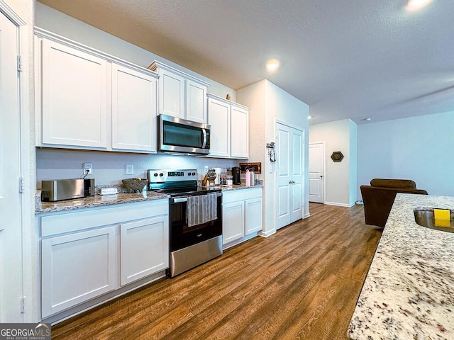 534 Meadows Farm Dr, Monroe, GA 30655 - kitchen featuring stainless steel appliances, dark wood-style flooring, white cabinetry, and light stone countertops