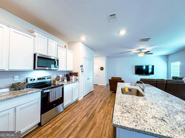 534 Meadows Farm Dr, Monroe, GA 30655 - kitchen with appliances with stainless steel finishes, white cabinets, a ceiling fan, wood finished floors, and a textured ceiling