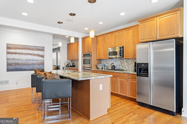 196 Mystic Ct, Atlanta, GA 30342 - kitchen with appliances with stainless steel finishes, an island with sink, recessed lighting, backsplash, and light wood-style flooring