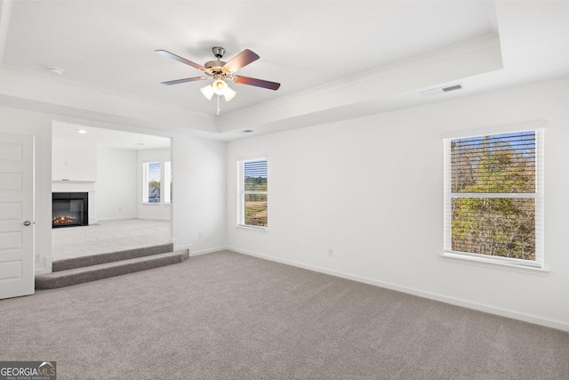 683 Edgar, Hampton, GA 30228 - unfurnished living room featuring carpet flooring, a tray ceiling, ceiling fan, a glass covered fireplace, and crown molding