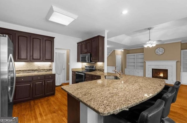 3737 Falls Trl, Winston, GA 30187 - kitchen featuring stainless steel appliances, a kitchen bar, ceiling fan, light wood-style floors, and a brick fireplace
