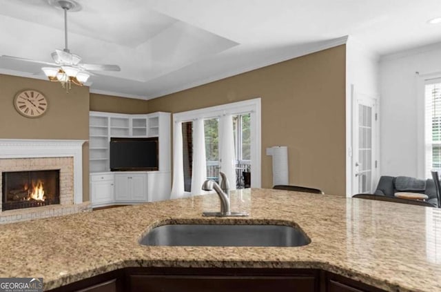 3737 Falls Trl, Winston, GA 30187 - kitchen with open floor plan, light stone counters, ceiling fan, ornamental molding, and a brick fireplace