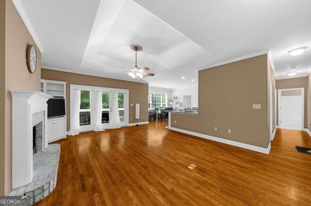 3737 Falls Trl, Winston, GA 30187 - unfurnished living room featuring a ceiling fan, wood finished floors, a fireplace with raised hearth, a raised ceiling, and ornamental molding