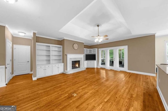 3737 Falls Trl, Winston, GA 30187 - unfurnished living room featuring ceiling fan, a raised ceiling, light wood-type flooring, a brick fireplace, and ornamental molding