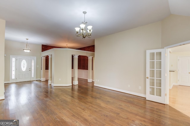 805 River Vly, Dacula, GA 30019 - unfurnished living room with decorative columns, wood finished floors, a chandelier, and vaulted ceiling