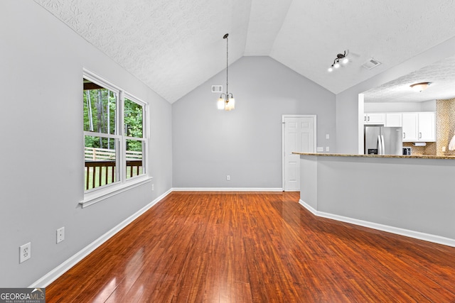 80 Austin Woods Dr, Senoia, GA 30276 - unfurnished living room featuring a textured ceiling, wood finished floors, lofted ceiling, and a chandelier