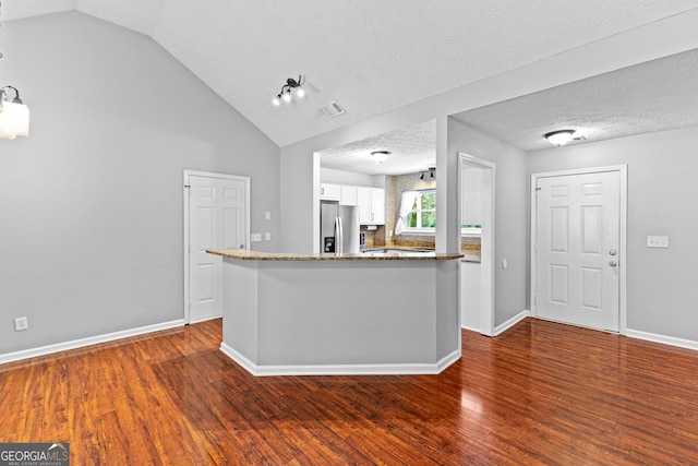 80 Austin Woods Dr, Senoia, GA 30276 - kitchen with stainless steel fridge, white cabinetry, dark stone counters, wood finished floors, and lofted ceiling