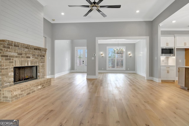 194 Forest Berry Ct Unit 98M2, Newnan, GA 30265 - unfurnished living room with a ceiling fan, ornamental molding, a brick fireplace, light wood finished floors, and a chandelier