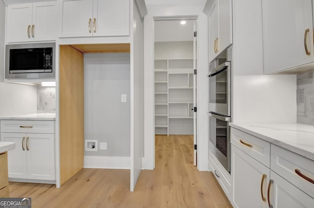 194 Forest Berry Ct Unit 98M2, Newnan, GA 30265 - kitchen featuring stainless steel appliances, light wood-style flooring, light stone counters, and white cabinetry