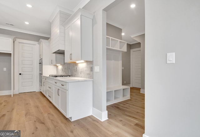 194 Forest Berry Ct Unit 98M2, Newnan, GA 30265 - kitchen featuring ornamental molding, tasteful backsplash, white cabinetry, stovetop, and light countertops