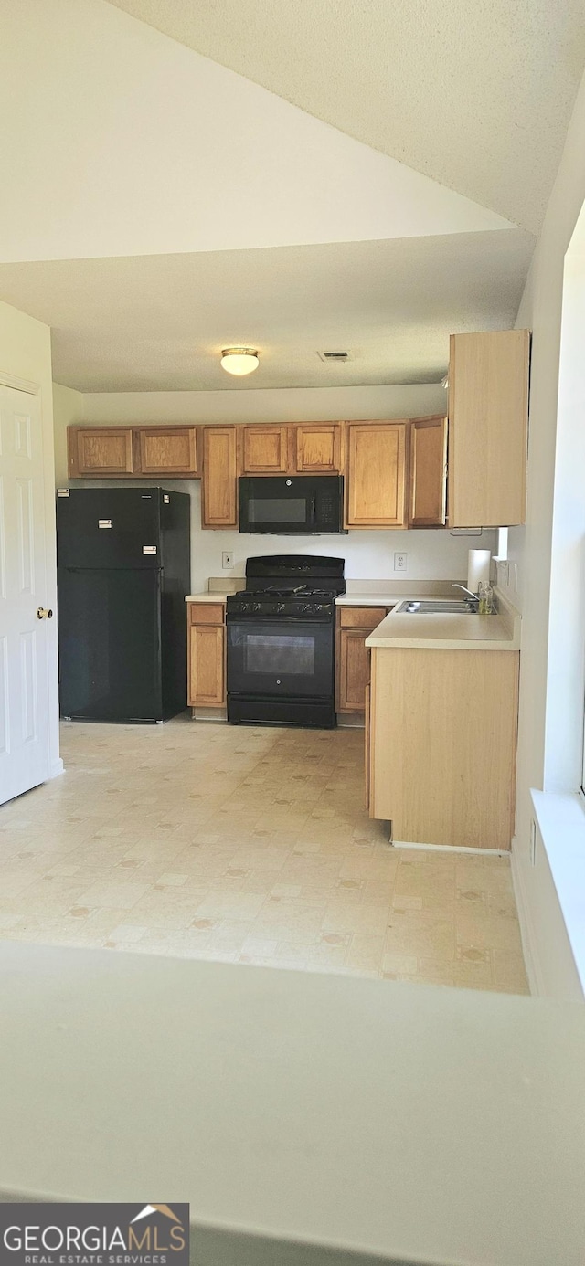 116 Ventura Trl, Stockbridge, GA 30281 - kitchen featuring black appliances, vaulted ceiling, light countertops, brown cabinets, and light floors