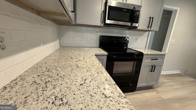 4550 Cypress Ridge Ct, Stone Mountain, GA 30083 - kitchen with stainless steel microwave, black electric range oven, light stone counters, and tasteful backsplash