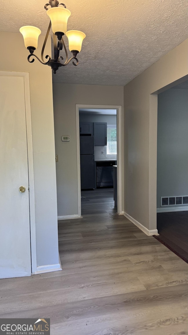 4550 Cypress Ridge Ct, Stone Mountain, GA 30083 - hall featuring wood finished floors, a chandelier, and a textured ceiling