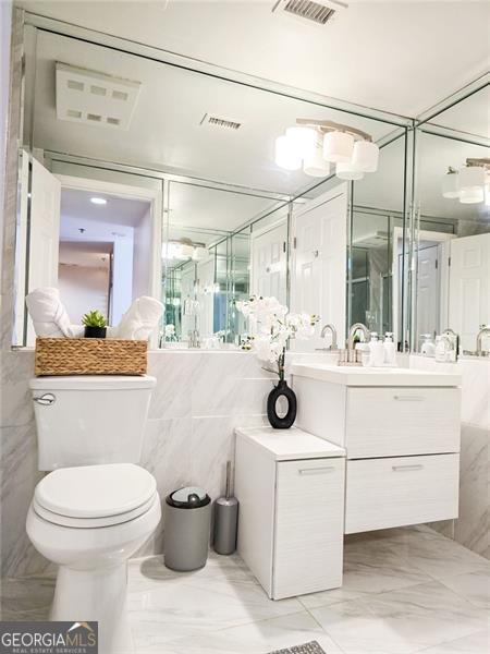 3481 Lakeside Unit 2204, Atlanta, GA 30326 - full bathroom with vanity, tile walls, and marble finish flooring