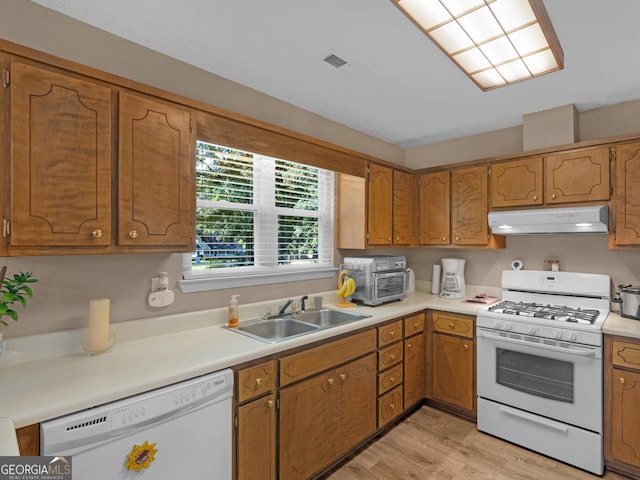 2866 Rosecommons Dr, Hampton, GA 30228 - kitchen featuring white appliances, under cabinet range hood, brown cabinets, and light wood-style floors