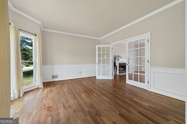 11 Chad Ct, Mcdonough, GA 30253 - empty room featuring crown molding, wood finished floors, french doors, a warm lit fireplace, and wainscoting