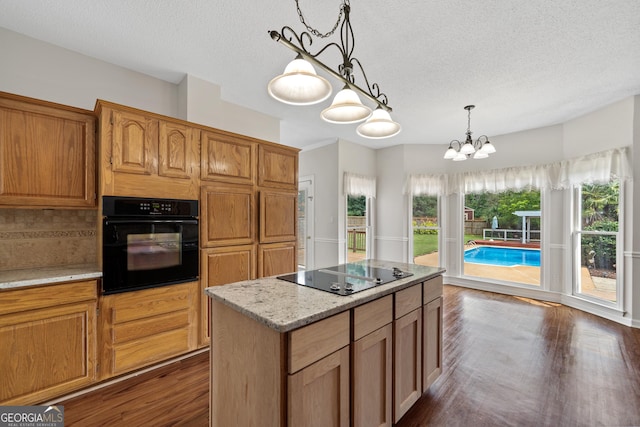 11 Chad Ct, Mcdonough, GA 30253 - kitchen with black appliances, a textured ceiling, dark wood finished floors, hanging light fixtures, and a kitchen island