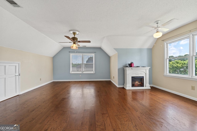 11 Chad Ct, Mcdonough, GA 30253 - unfurnished living room featuring ceiling fan, vaulted ceiling, wood finished floors, a textured ceiling, and a warm lit fireplace
