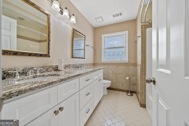 11 Chad Ct, Mcdonough, GA 30253 - full bathroom featuring double vanity, a shower, tile patterned floors, tile walls, and a wainscoted wall