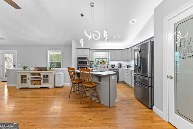152 Bear Creek Rd, Moreland, GA 30259 - kitchen featuring stainless steel appliances, a breakfast bar area, light wood-type flooring, a center island, and lofted ceiling