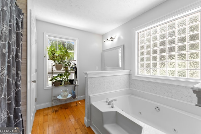 152 Bear Creek Rd, Moreland, GA 30259 - full bathroom featuring plenty of natural light, a jetted tub, hardwood / wood-style floors, and a textured ceiling