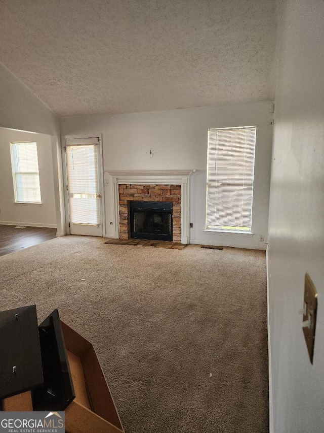 3059 Brass Dr, Austell, GA 30106 - unfurnished living room with a textured ceiling, carpet floors, a brick fireplace, and lofted ceiling