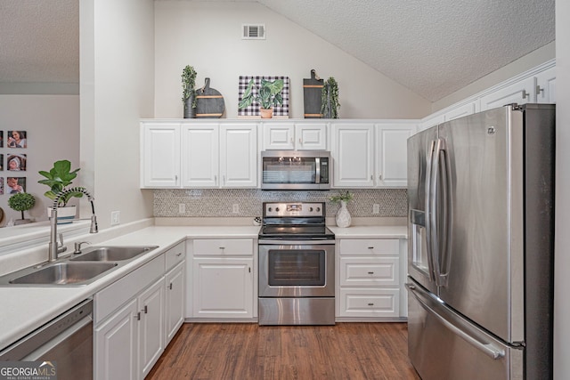 231 Brookstone Ct, Rincon, GA 31326 - kitchen featuring stainless steel appliances, a textured ceiling, lofted ceiling, white cabinets, and decorative backsplash