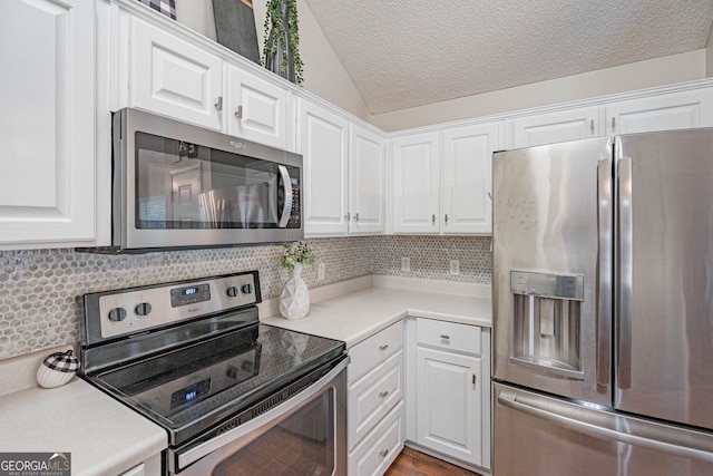 231 Brookstone Ct, Rincon, GA 31326 - kitchen with stainless steel appliances, decorative backsplash, vaulted ceiling, white cabinets, and a textured ceiling