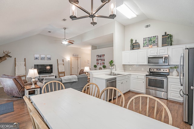 231 Brookstone Ct, Rincon, GA 31326 - kitchen featuring appliances with stainless steel finishes, lofted ceiling, open floor plan, wood finished floors, and white cabinets
