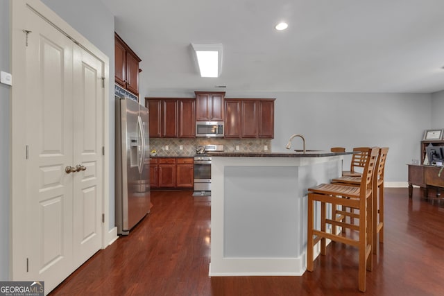 14 Hammock Ridge Dr, Newnan, GA 30265 - kitchen with appliances with stainless steel finishes, backsplash, dark wood-style floors, a breakfast bar area, and dark countertops