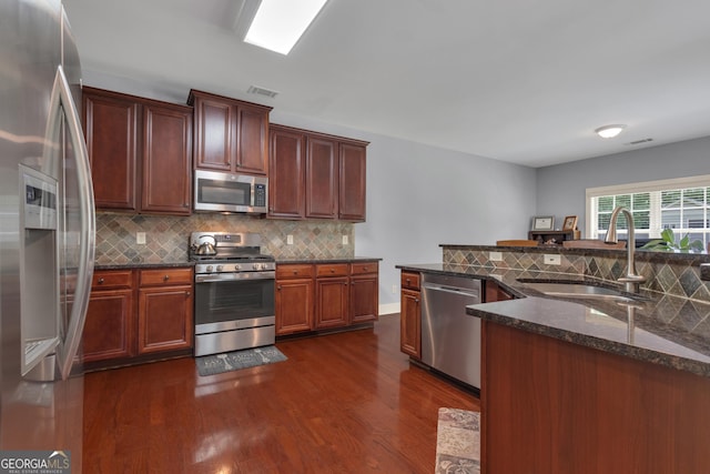 14 Hammock Ridge Dr, Newnan, GA 30265 - kitchen featuring appliances with stainless steel finishes, dark wood finished floors, decorative backsplash, and dark stone counters