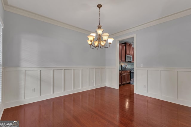 14 Hammock Ridge Dr, Newnan, GA 30265 - unfurnished dining area featuring a chandelier, a decorative wall, crown molding, dark wood-style floors, and wainscoting
