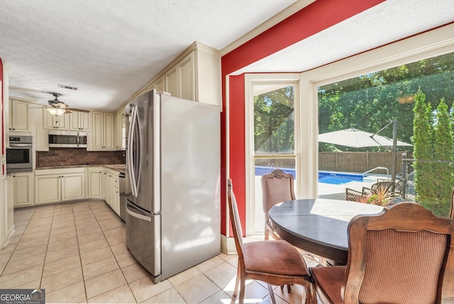 234 Crumbley Rd, Mcdonough, GA 30252 - kitchen featuring cream cabinetry, stainless steel appliances, light tile patterned flooring, a ceiling fan, and tasteful backsplash