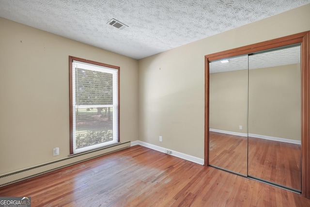 234 Crumbley Rd, Mcdonough, GA 30252 - unfurnished bedroom featuring a baseboard radiator, wood finished floors, a closet, and a textured ceiling