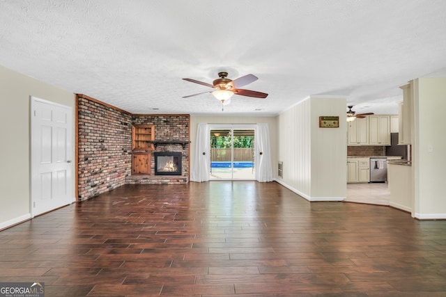 234 Crumbley Rd, Mcdonough, GA 30252 - unfurnished living room with ceiling fan, wood finished floors, a brick fireplace, brick wall, and a textured ceiling