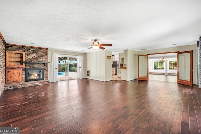 234 Crumbley Rd, Mcdonough, GA 30252 - unfurnished living room featuring a chandelier, healthy amount of natural light, dark wood-type flooring, a brick fireplace, and a textured ceiling