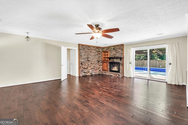 234 Crumbley Rd, Mcdonough, GA 30252 - unfurnished living room with ceiling fan, wood finished floors, brick wall, a brick fireplace, and a textured ceiling