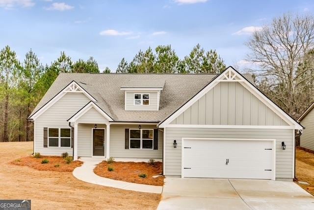 32 Sourwood Dr, Mansfield, GA 30055 - view of front facade with board and batten siding, an attached garage, concrete driveway, and a shingled roof