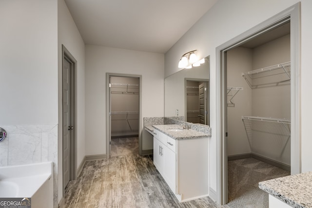 32 Sourwood Dr, Mansfield, GA 30055 - bathroom featuring vanity, a spacious closet, a tub to relax in, and wood finished floors