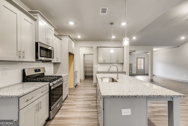 32 Sourwood Dr, Mansfield, GA 30055 - kitchen featuring appliances with stainless steel finishes, light wood-style floors, a kitchen island with sink, tasteful backsplash, and recessed lighting