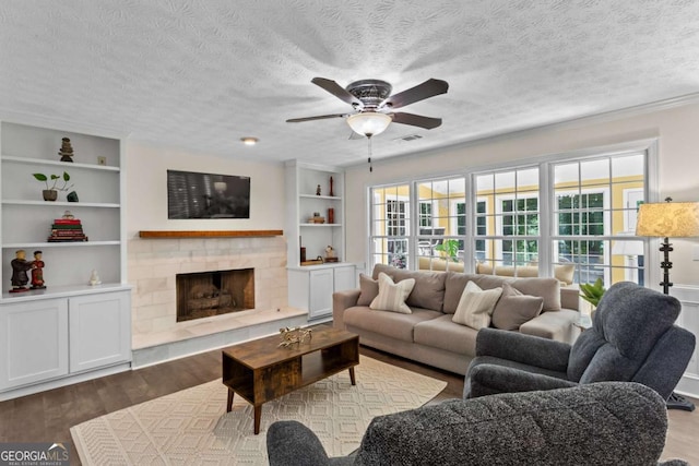 4961 Thornwood Trce NW, Acworth, GA 30102 - living room featuring a ceiling fan, wood finished floors, a tiled fireplace, a textured ceiling, and built in features