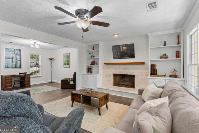 4961 Thornwood Trce NW, Acworth, GA 30102 - living room featuring wood finished floors, built in shelves, a ceiling fan, a tile fireplace, and a textured ceiling