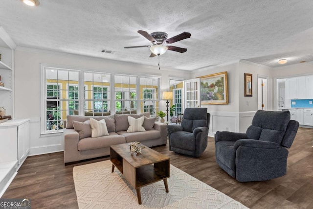 4961 Thornwood Trce NW, Acworth, GA 30102 - living room with a ceiling fan, crown molding, dark wood-type flooring, a decorative wall, and a textured ceiling