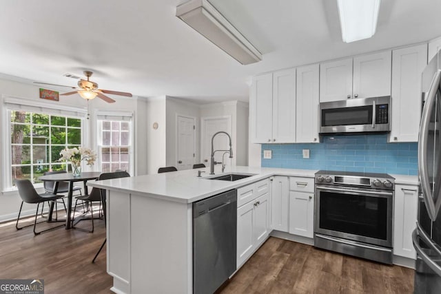 4961 Thornwood Trce NW, Acworth, GA 30102 - kitchen with stainless steel appliances, a peninsula, light countertops, white cabinets, and crown molding