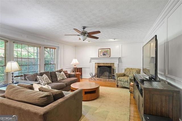 7045 Hunters Knl NE, Sandy Springs, GA 30328 - living room featuring a decorative wall, light wood-style flooring, crown molding, a ceiling fan, and a fireplace