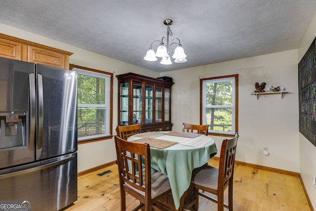 220 Gamble Dr, Carrollton, GA 30116 - dining space featuring light wood-style floors, a chandelier, healthy amount of natural light, and a textured ceiling