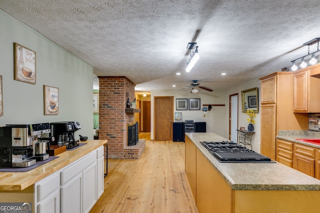 220 Gamble Dr, Carrollton, GA 30116 - kitchen featuring black gas cooktop, a ceiling fan, a textured ceiling, a kitchen island, and a fireplace