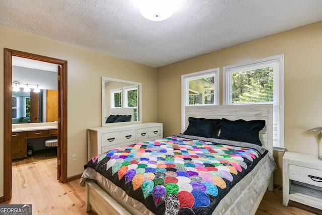 220 Gamble Dr, Carrollton, GA 30116 - bedroom featuring light wood finished floors, multiple windows, ensuite bathroom, and a textured ceiling